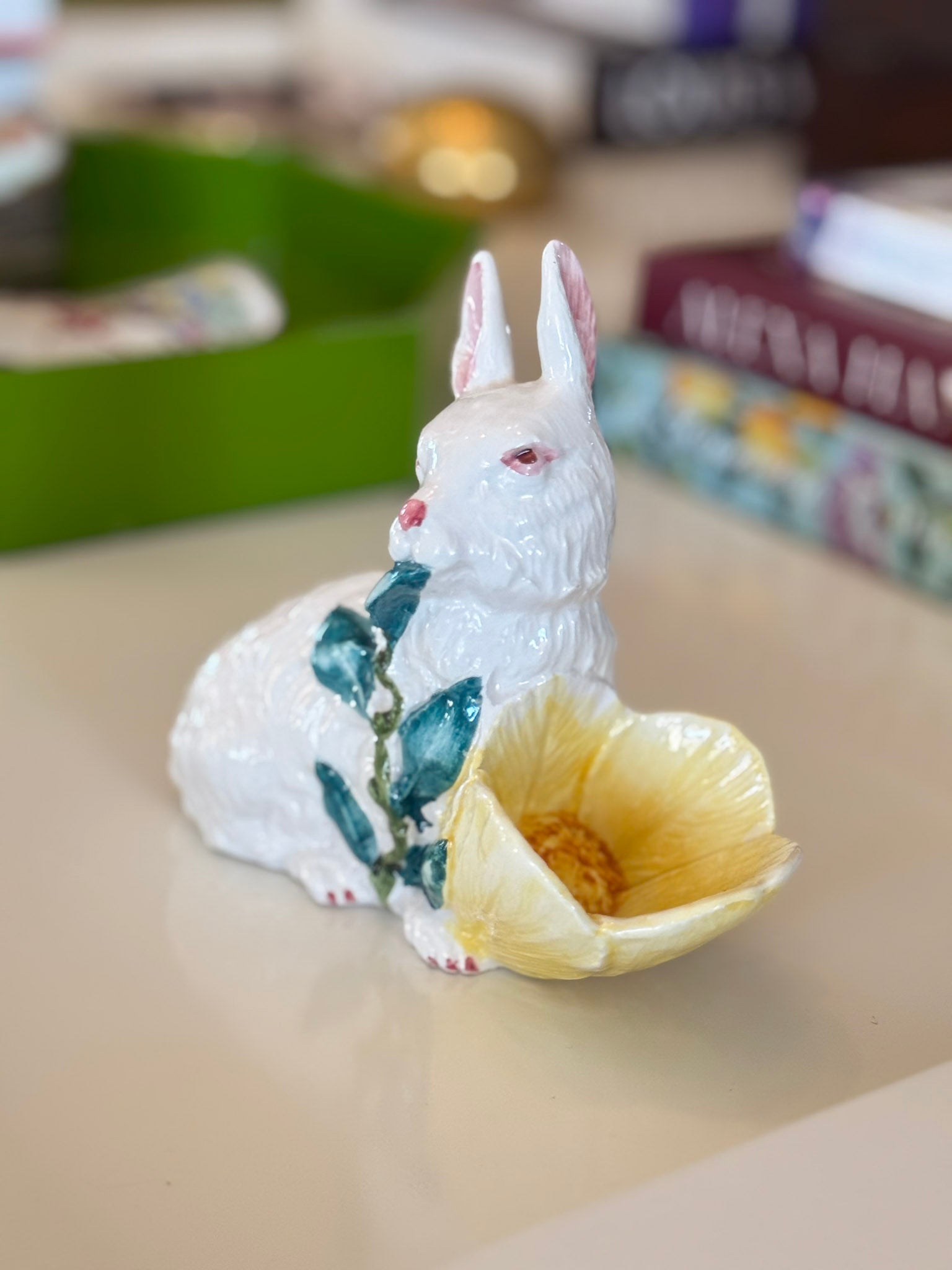 White ceramic rabbit figurine with a flower on a beige surface