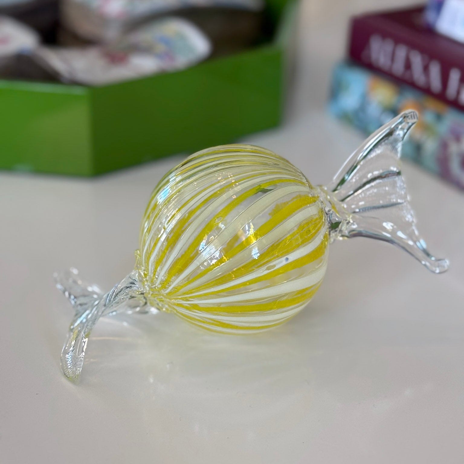 Glass candy with yellow and white stripes on a light surface