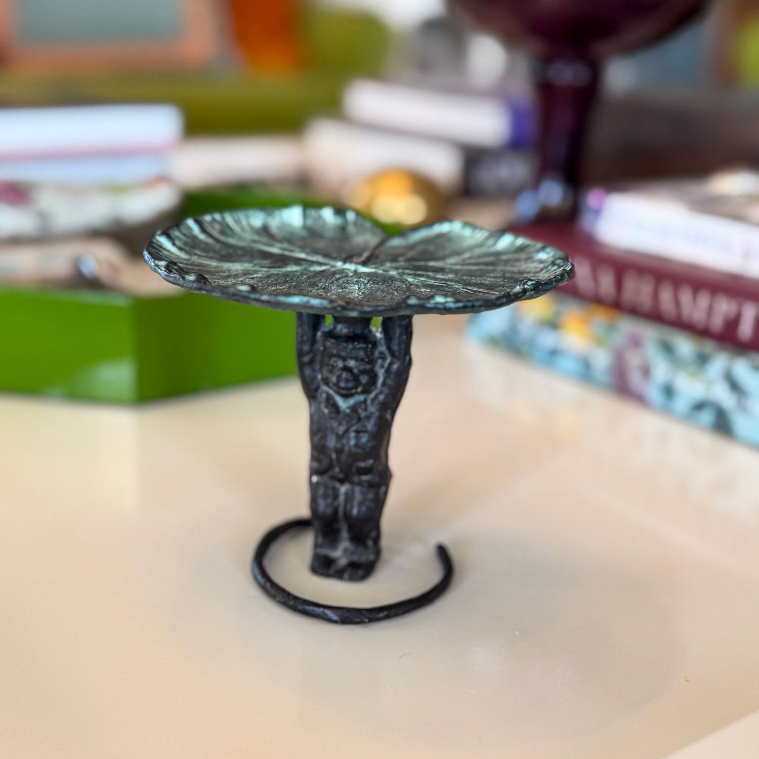 Decorative candle holder on a table with books and a glass in the background